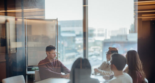 Photo of five people sitting around a table in a conference room